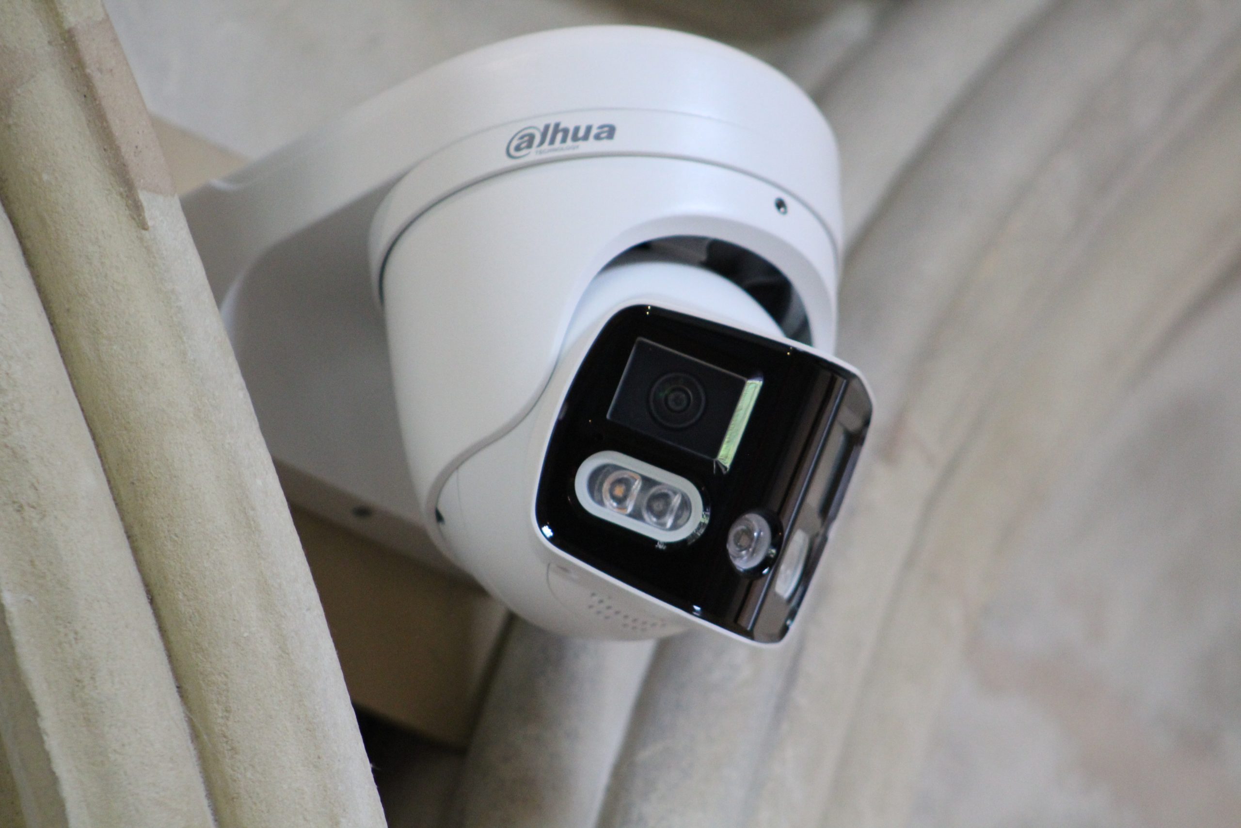 White dome style CCTV security camera mounted on an interior wall or ceiling, showing a visible lens and integrated infrared lights within the housing.